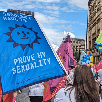 Image of group of people flying flags with pride at Manchester Pride Parade.